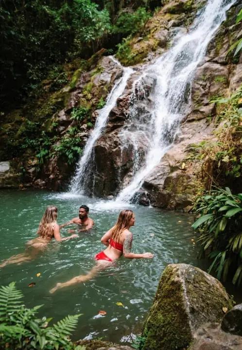 Cascada tropical en Minca Sierra Nevada con viajeros nadando en piscinas naturales rodeadas de selva.